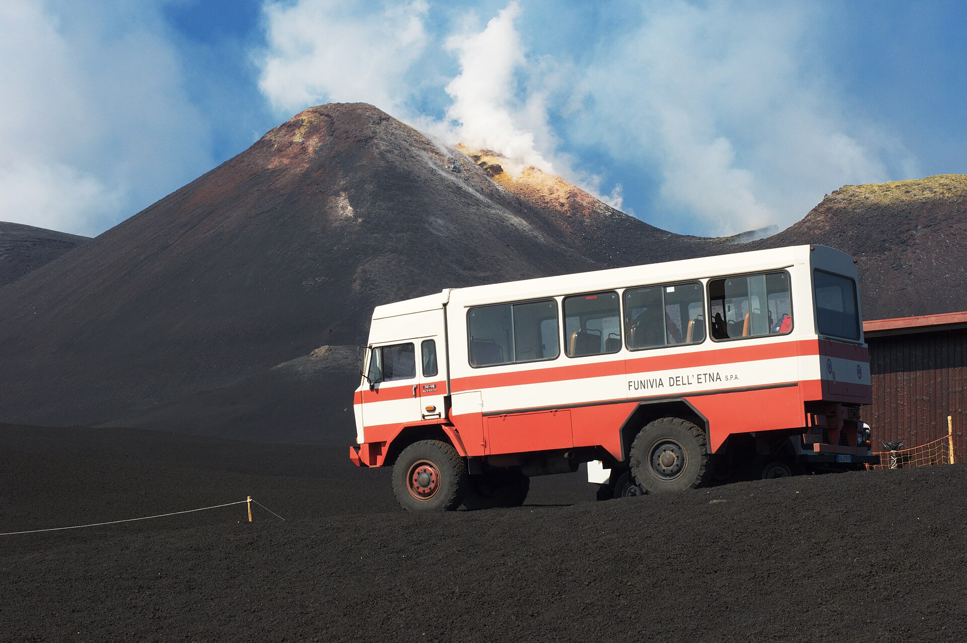 Bus fuoristrada 4x4 della funivia dell'Etna con un cratere fumante sullo sfondo