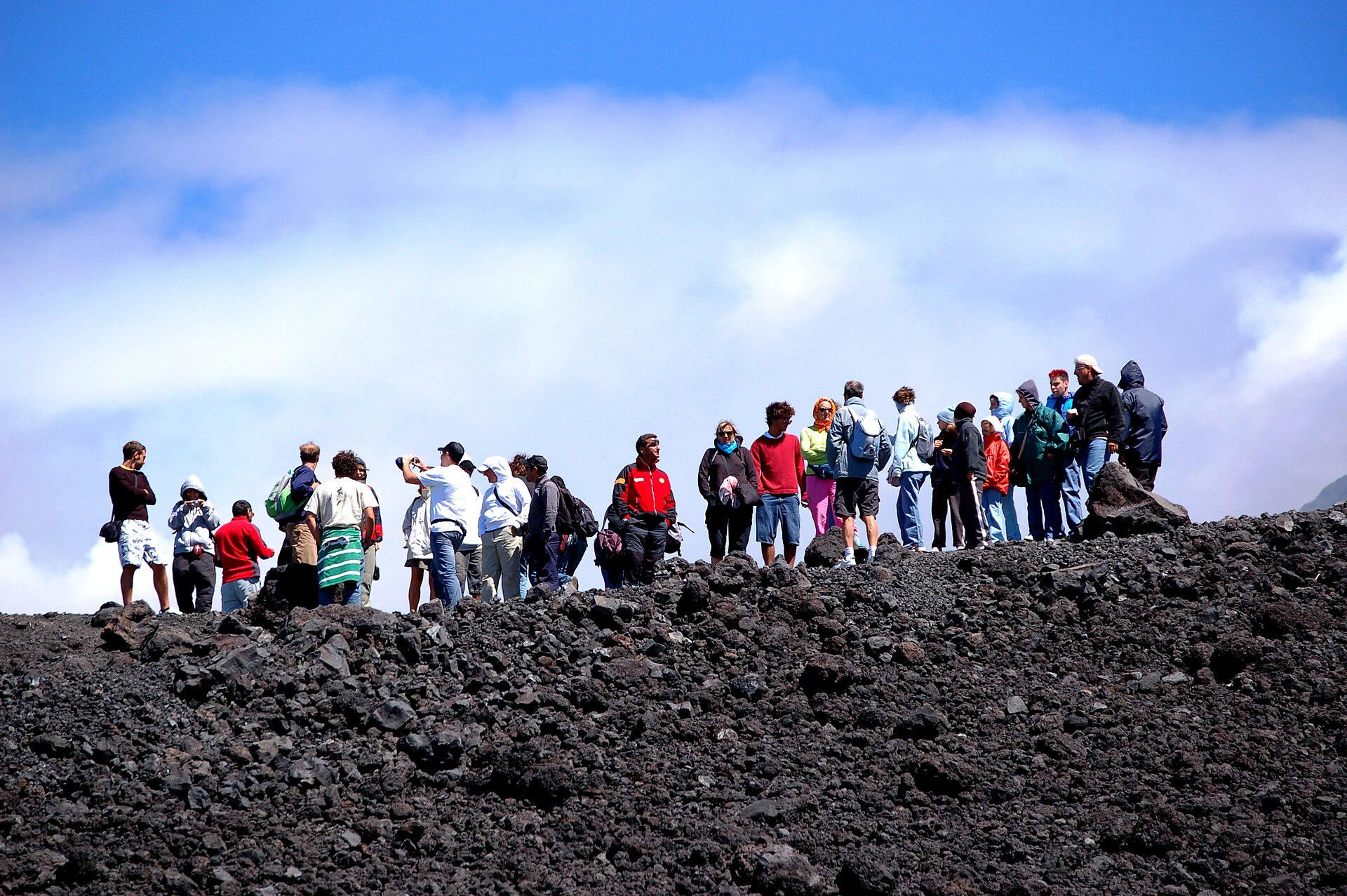 Gruppo di escursionisti con giacche e zaini sul terreno di lapilli neri dell'Etna