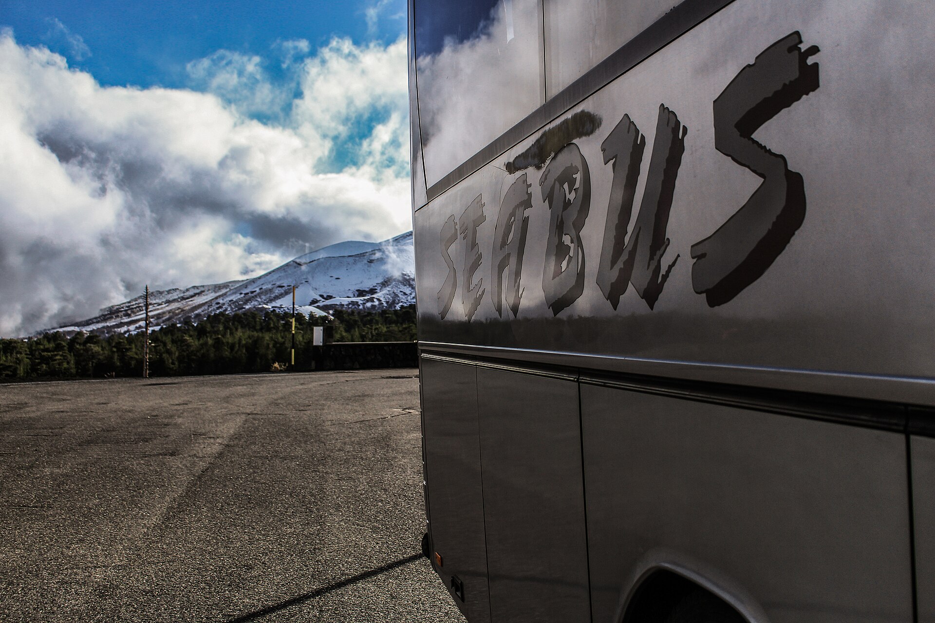 Bus turistico nel piazzale di Piano Provenzana con l'Etna innevata sullo sfondo