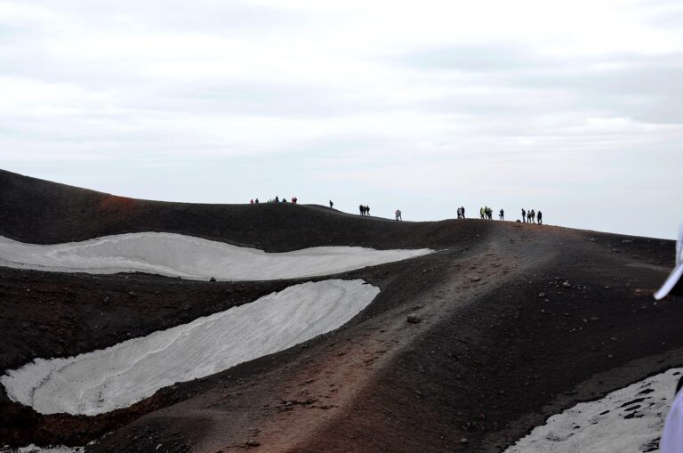 Cresta dell'Etna con chiazze di neve residua e escursionisti in lontananza